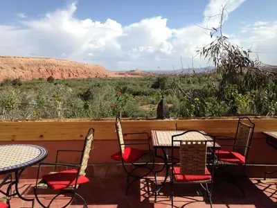 a patio with tables and chairs and a view of the desert at Auberge Ayouze in Aït Ben Haddou
