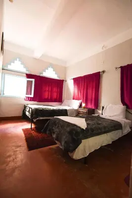 a bedroom with two beds and red curtains at Etoile des Gorges in Aït Baha