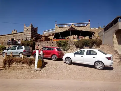 three cars parked in a parking lot in front of a building at Auberge Amazigh in Tamtetoucht