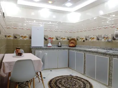 a kitchen with white cabinets and a table with chairs at DIAAFATE TANNIRTE in Khenifra
