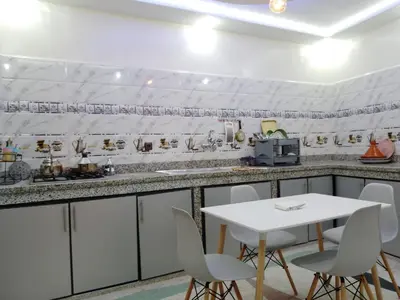 a white kitchen with a white table and chairs at DIAAFATE TANNIRTE in Khenifra