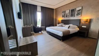 a hotel room with a bed and a table at Hotel Jaouharat Ismaili in Meknès