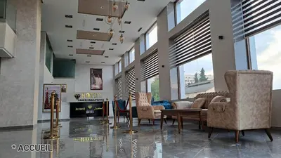 a living room with chairs and a table and a fireplace at Hotel Jaouharat Ismaili in Meknès