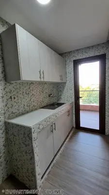 a kitchen with white cabinets and a sliding door at Hotel Jaouharat Ismaili in Meknès