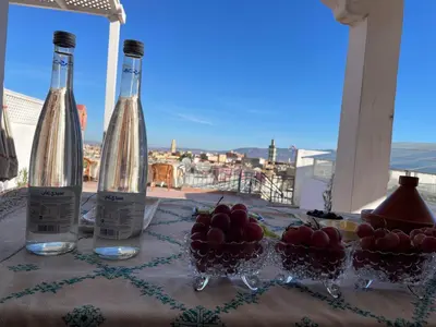 two bottles of wine and bowls of fruit on a table at DAR ALKATIB MEKNES in Meknès