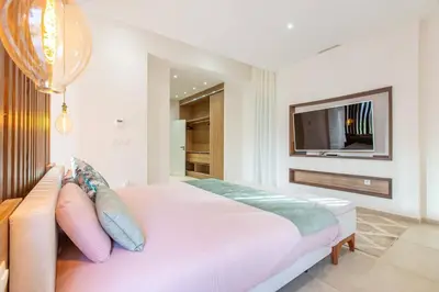 a white bedroom with a bed and a tv at Villa Safiya, luxe et détente, jeux, cuisinière in Marrakech