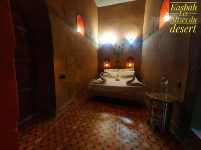 a bedroom with a bed with lights on the wall at Kasbah Les Alizes Du Desert in Mhamid
