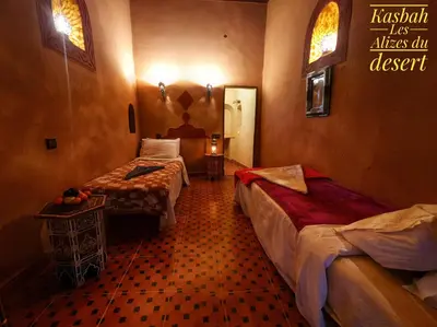 a room with two beds in a hotel room at Kasbah Les Alizes Du Desert in Mhamid