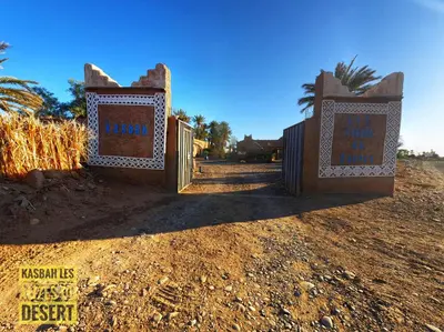 a gate in the middle of a dirt road at Kasbah Les Alizes Du Desert in Mhamid