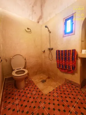 a bathroom with a toilet and a shower with a window at Kasbah Les Alizes Du Desert in Mhamid