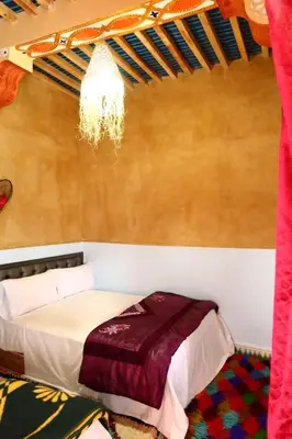 a bedroom with a bed and a chandelier at gîte d'étape ziz oasis in Achbarou