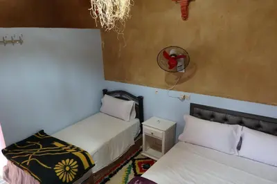 a bedroom with two beds and a mirror on the wall at gîte d'étape ziz oasis in Achbarou