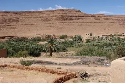 a village in the desert with a mountain in the background at gîte d'étape ziz oasis in Achbarou