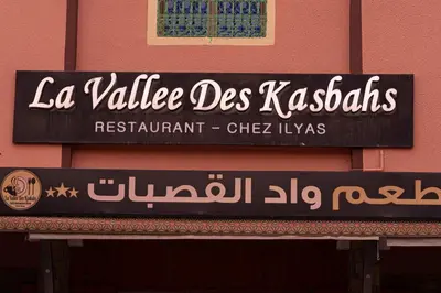 a sign for a restaurant on the side of a building at HOTEL LA VALLEE DES KASBAHS CHEZ ILYAS in Tinerhir