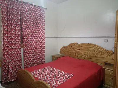 a bedroom with a wooden bed with a red blanket at Dar badiawarda in Azilal