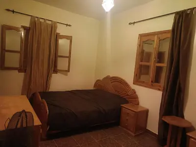 a bedroom with a bed and a window and a table at Dar badiawarda in Azilal