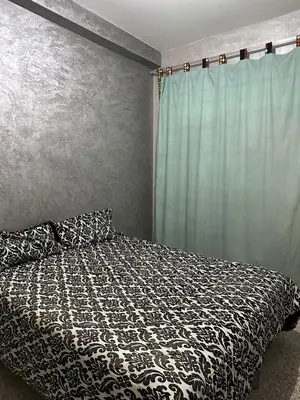 a bedroom with a bed with a black and white comforter at NADIA BELVUE 3 in Meknès