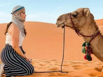 a woman in the desert with a camel at Desert Paradise Luxury Camp in Merzouga