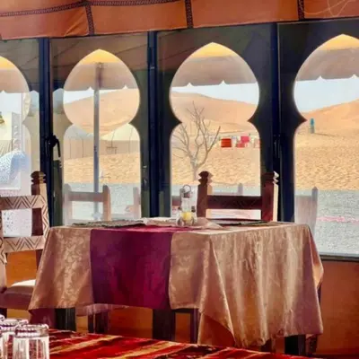 a table in a room with a view of the desert at Desert Paradise Luxury Camp in Merzouga