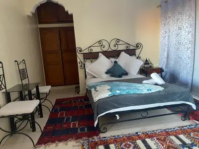 a bedroom with a bed and a table and a chair at APPART AIGLE HOTEL in Ouarzazate