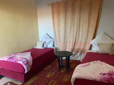 a room with two beds and a table and a window at APPART AIGLE HOTEL in Ouarzazate