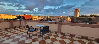 a balcony with a table and chairs and a view of a city at Residence Imlil Ouarzazate in Ouarzazate