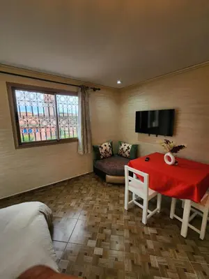 a room with a red table and a couch at Residence Imlil Ouarzazate in Ouarzazate
