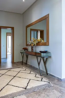 a table with a mirror and a vase with flowers at Villa Roseraie Isabella in Marrakech