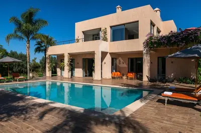 a villa with a swimming pool in front of a house at Villa Roseraie Isabella in Marrakech
