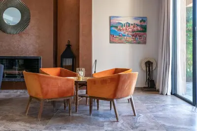 a dining room with a table and orange chairs at Villa Roseraie Isabella in Marrakech