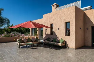 a patio with couches and an umbrella and a table at Villa Roseraie Isabella in Marrakech