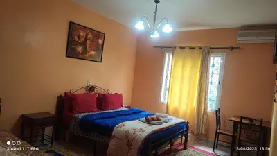 a bedroom with a bed with red and blue sheets and a window at Maison Touria in Ouzoud