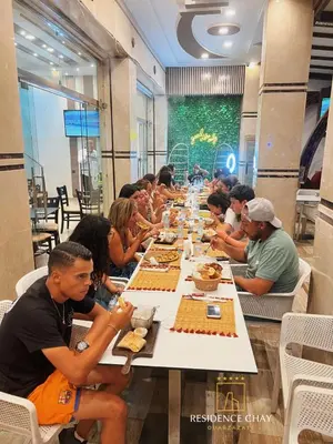 a group of people sitting at a long table eating food at Residence Chay - Appartement de luxe in Ouarzazate