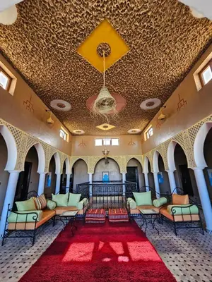 a room with chairs and a ceiling with a red rug at Riad Merzouga Dunes in Merzouga
