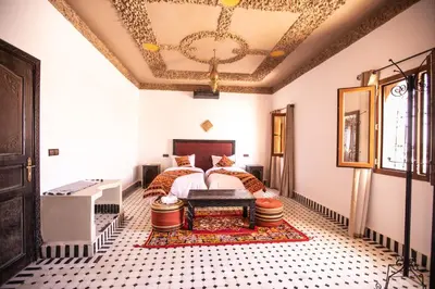 a bedroom with a bed and a chandelier at Riad Merzouga Dunes in Merzouga