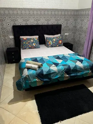 a bedroom with a bed with a blue comforter and pillows at A appartement in Fès