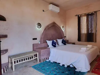 a bedroom with a large bed and a chair at Maison Hassan Merzouga in Merzouga