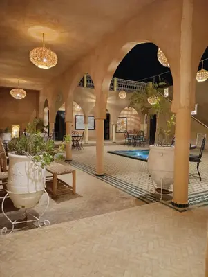 a lobby with a pool and tables and potted plants at Maison Hassan Merzouga in Merzouga