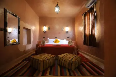 a hotel room with a bed and twoupholessential at Maison Hassan Merzouga in Merzouga