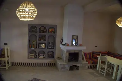 a living room with a fireplace and a couch at Maison Hassan Merzouga in Merzouga