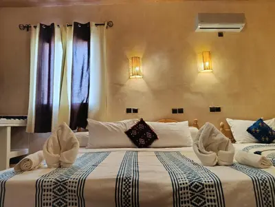 two beds in a hotel room with windows at Maison Hassan Merzouga in Merzouga