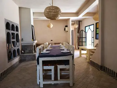 a dining room with a long table and chairs at Maison Hassan Merzouga in Merzouga