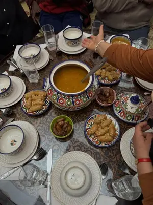 a table topped with plates of food and bowls of soup at Jouba Luxury Camp in Merzouga