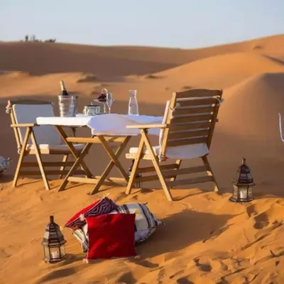 a table and chairs in the sand in the desert at Jouba Luxury Camp in Merzouga