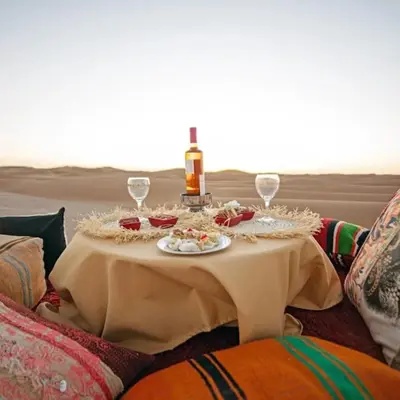 a table with a bottle of wine and glasses on it at Jouba Luxury Camp in Merzouga