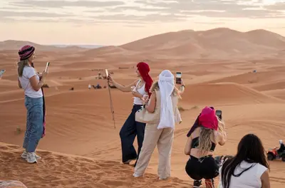 a group of people taking pictures in the desert at Jouba Luxury Camp in Merzouga