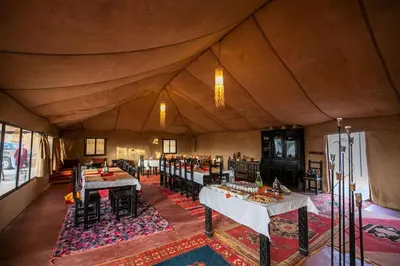 a dining room in a tent with tables and chairs at Jouba Luxury Camp in Merzouga