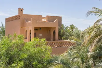 a house with palm trees in front of it at Auberge Ksar Jallal in Ksar Oled Cherki