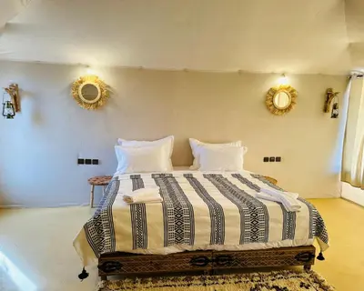 a bedroom with a large bed with two mirrors on the wall at spirit desert camp in Merzouga