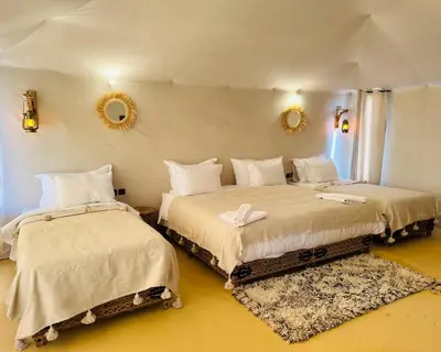 a bedroom with two beds and a mirror at spirit desert camp in Merzouga